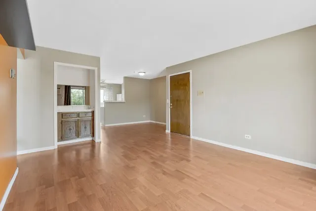 a view of an empty room with window and wooden floor
