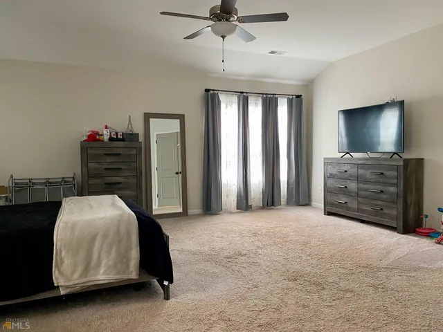 a bedroom with a bed and a flat tv screen on dresser