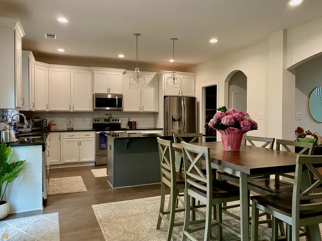 a kitchen with stainless steel appliances kitchen island granite countertop a table and chairs in it