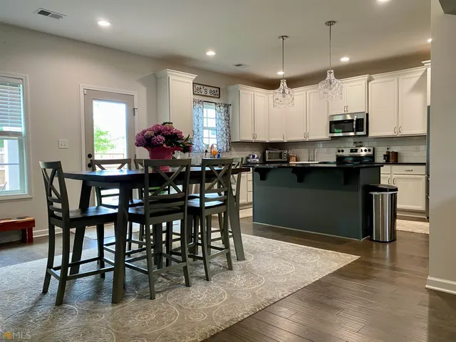 a kitchen with stainless steel appliances granite countertop a table chairs sink refrigerator and microwave