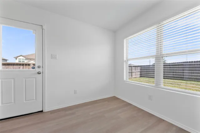 a view of an empty room with wooden floor and a window