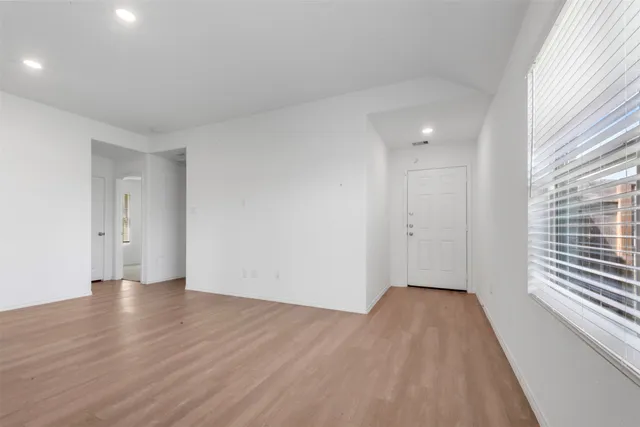 a view of an empty room with wooden floor and a window