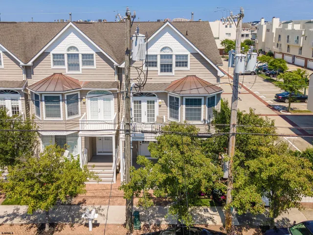 a view of white house with a yard and potted plants