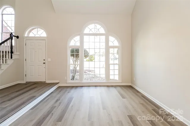 an empty room with wooden floor mirror and windows
