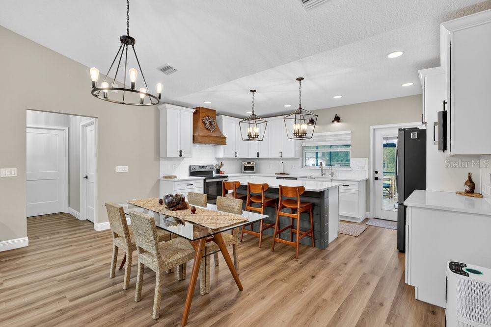 9054 Lincoln Road St. Cloud, FL 34773 - Photo 6 of 33 a kitchen with stainless steel appliances kitchen island granite countertop a table chairs and a refrigerator