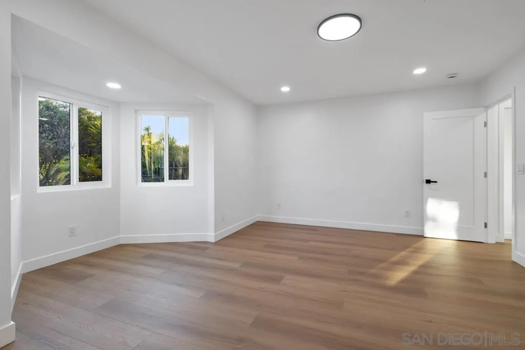 4516 Shade Road La Mesa, CA 91941 - Photo 19 of 33 an empty room with wooden floor and windows