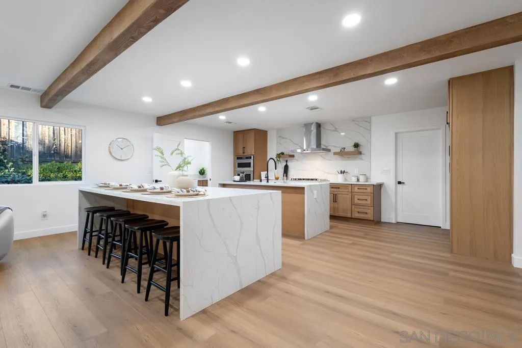 4516 Shade Road La Mesa, CA 91941 - Photo 5 of 33 a kitchen with kitchen island granite countertop wooden floors and white cabinets
