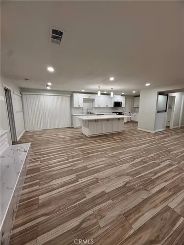 a view of a kitchen with kitchen island a sink wooden floor and a stove