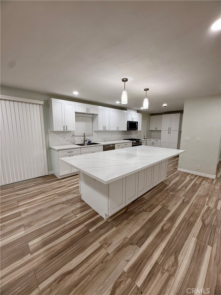 19825 Smith Road Perris, CA 92570 - Photo 4 of 16 a large white kitchen with kitchen island a sink stainless steel appliances and cabinets