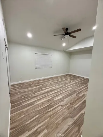 en empty room with wooden floor and fan