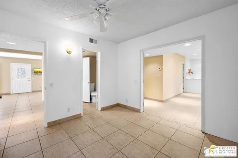 an empty room with kitchen and chandelier fan