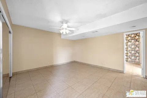 an empty room with windows and chandelier fan