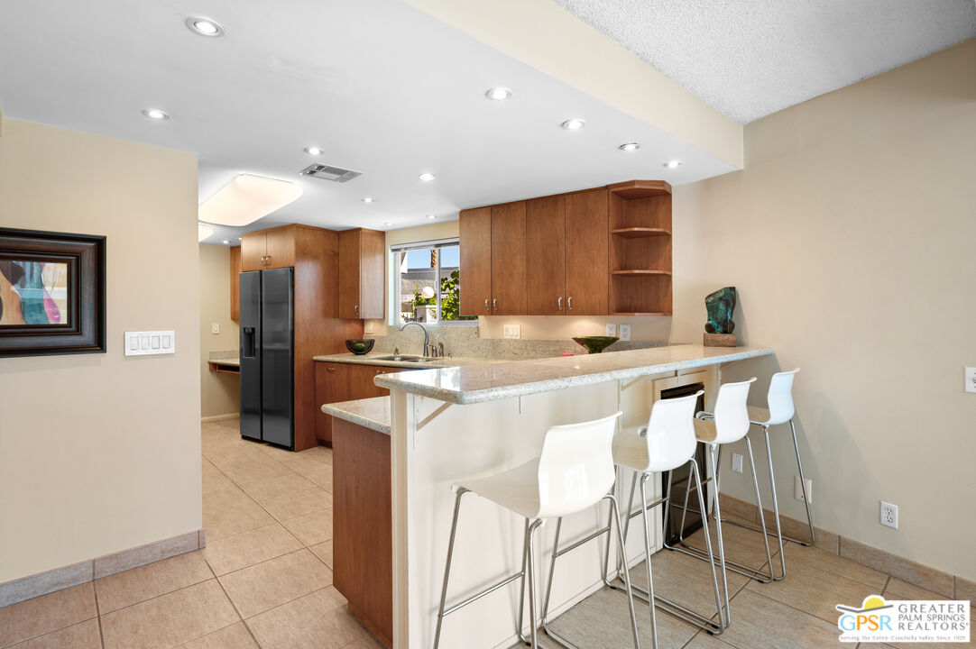 2033 Ramon Road, Unit 2C Palm Springs, CA 92264 - Photo 9 of 35 a kitchen with stainless steel appliances kitchen island granite countertop a refrigerator and a stove top oven