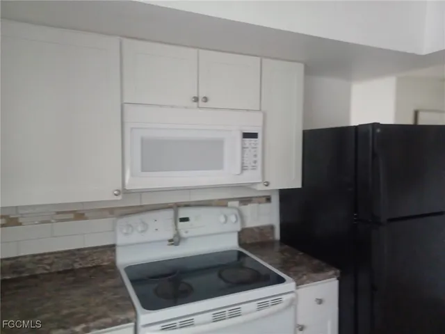 a kitchen with granite countertop white cabinets and refrigerator
