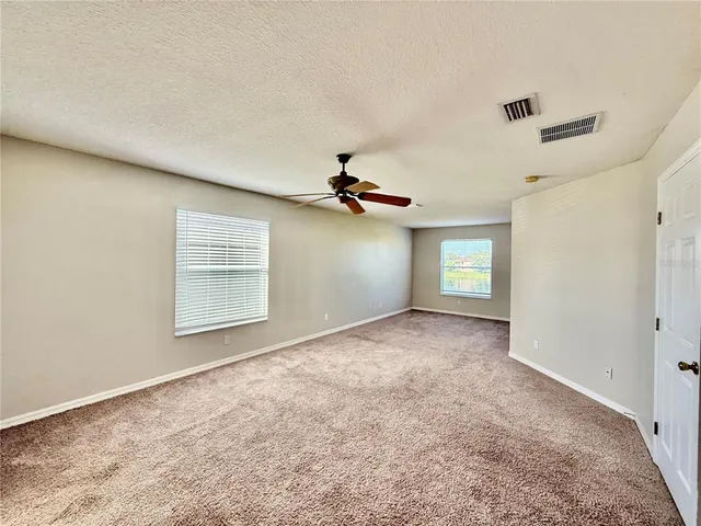 an empty room with windows and fan