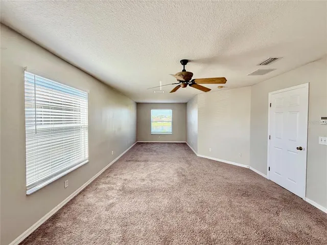 a view of empty room with windows and ceiling fan