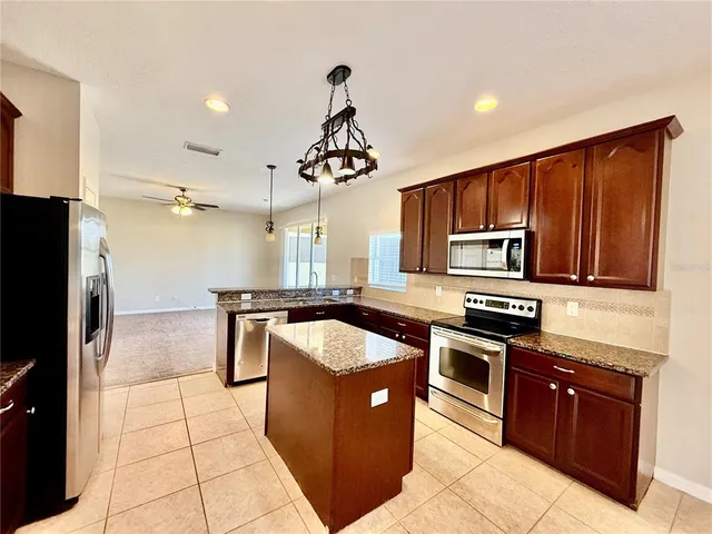 a kitchen with stainless steel appliances granite countertop a stove refrigerator sink and microwave