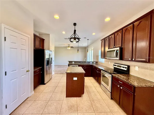a kitchen with stainless steel appliances granite countertop a refrigerator a stove top oven and sink