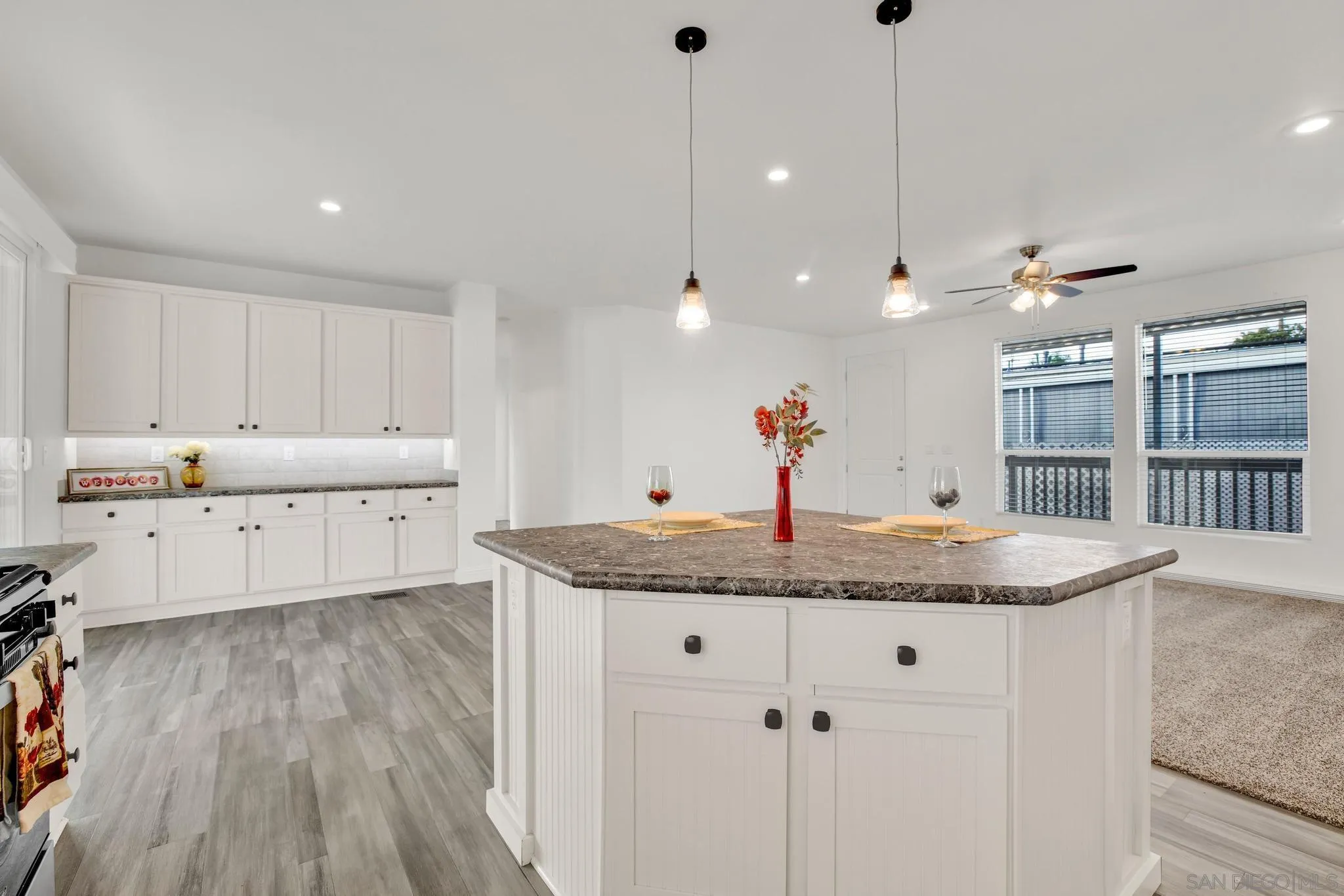 2515 Sweetwater Road, Unit 76 Spring Valley, CA 91977 - Photo 8 of 31 a kitchen with stainless steel appliances granite countertop a sink a oven a dining table and chairs with wooden floor