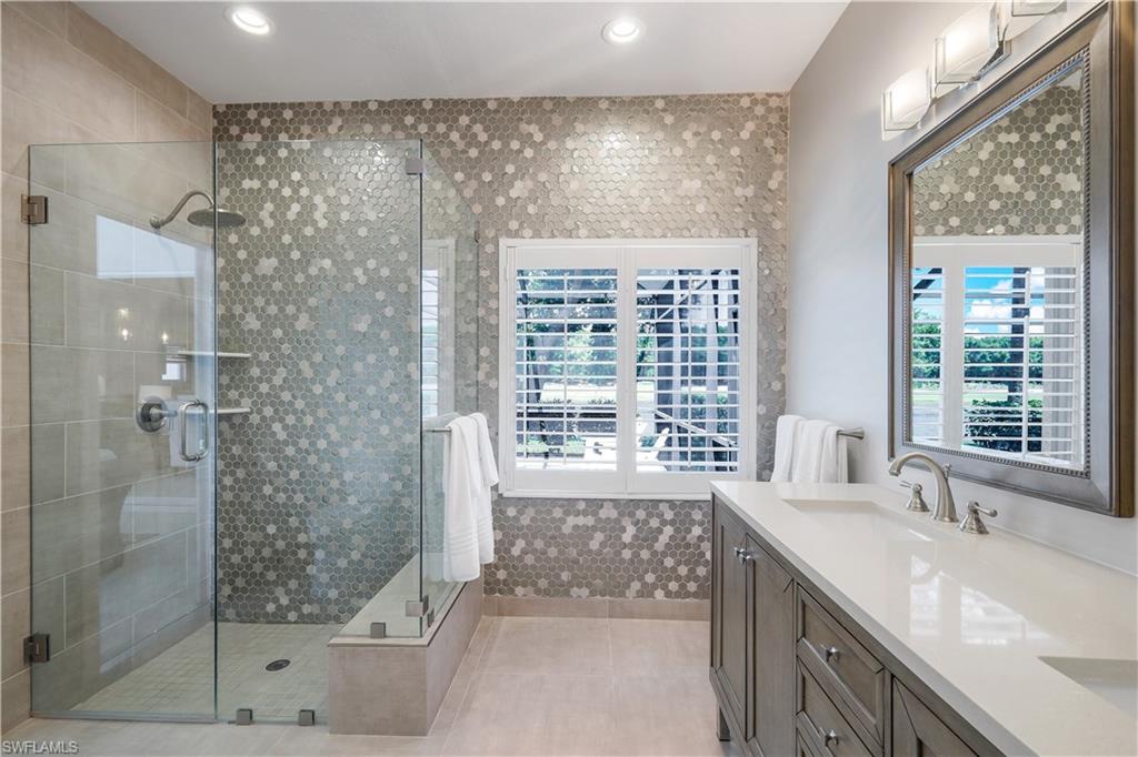 17945 Modena Road Miromar Lakes, FL 33913 - Photo 13 of 24 a bathroom with a granite countertop sink a large mirror a shower and a bathtub