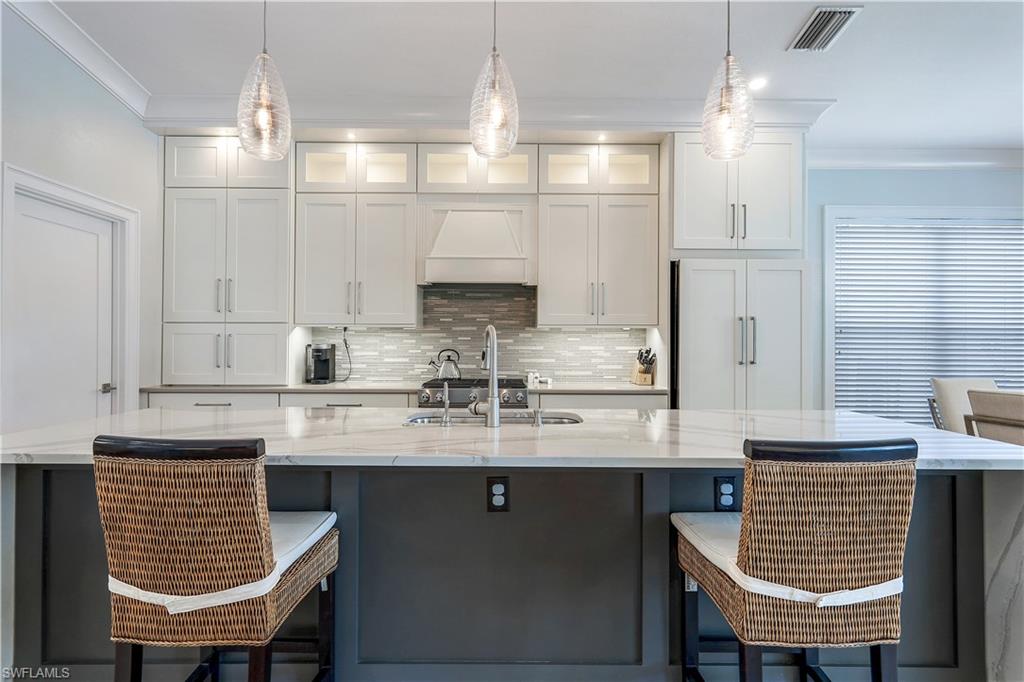 17945 Modena Road Miromar Lakes, FL 33913 - Photo 7 of 24 a kitchen with stainless steel appliances granite countertop a sink chairs and cabinets