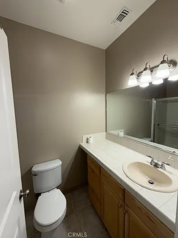 a bathroom with a toilet sink vanity granite and mirror