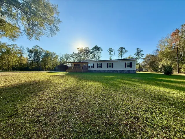 a view of a large pool with lawn chairs and a big yard