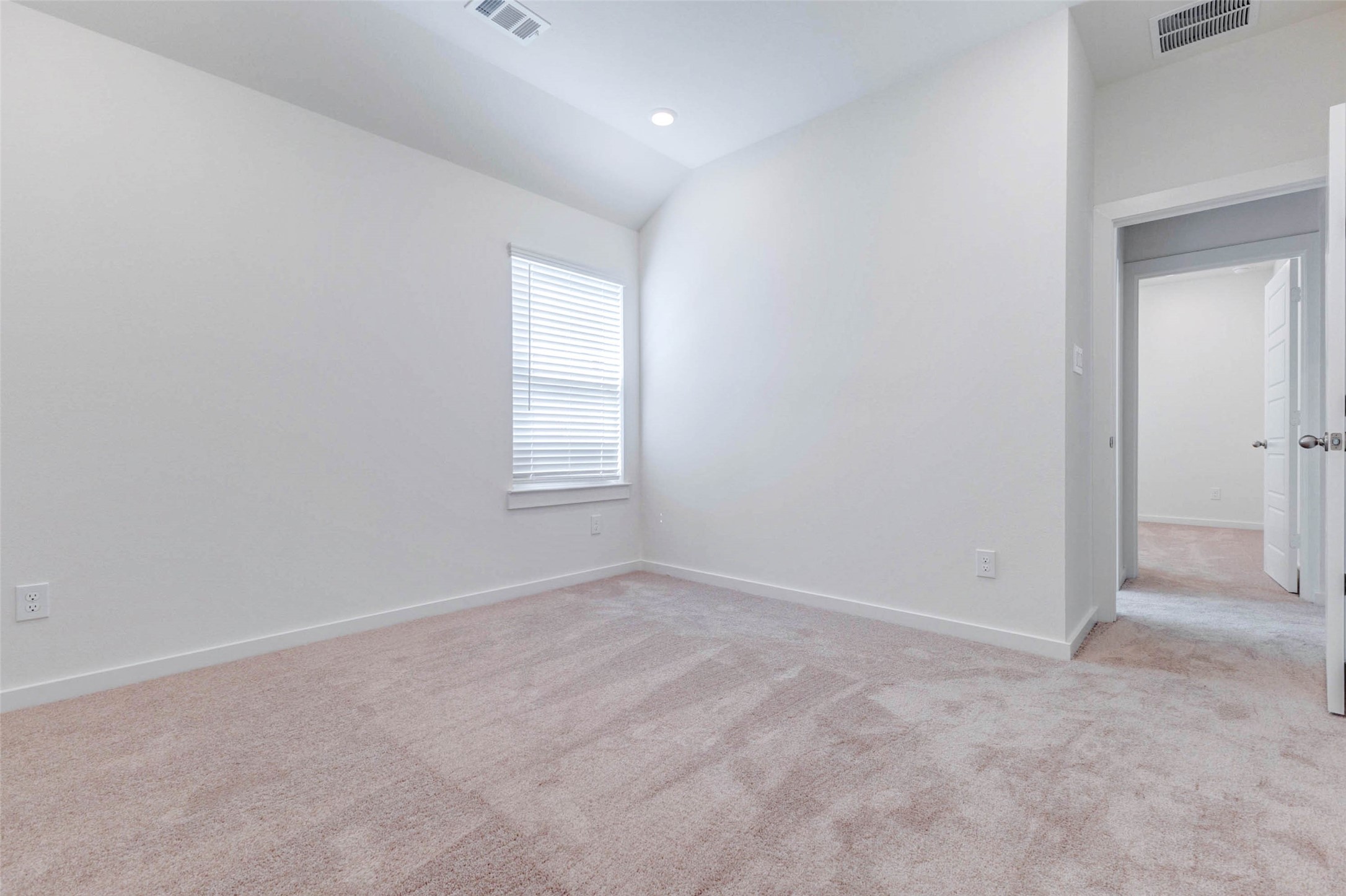 6467 Escondido Drive Rosharon, TX 77583 - Photo 25 of 32 Bright secondary bedroom with soft carpet, high ceiling, recessed lighting, window with blinds, and neutral walls. The open floor area allows flexible furniture placement, while the adjoining doorway connects easily to the rest of the bedroom wing. This room is ideal for a guest suite, child’s bedroom, nursery, home office, or quiet hobby space.