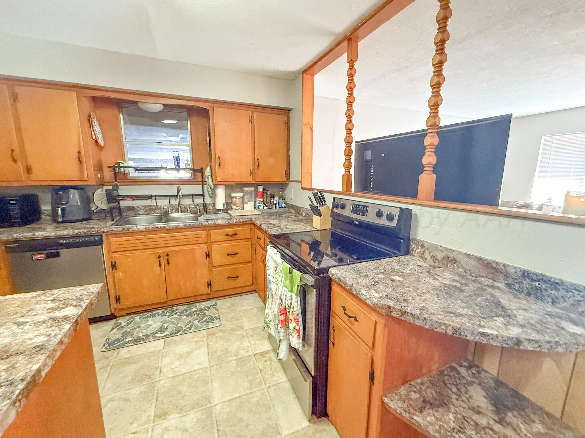 702 South Canadian Street Wheeler, TX 79096 - Photo 12 of 47 a kitchen with a stove a sink and a wooden cabinets