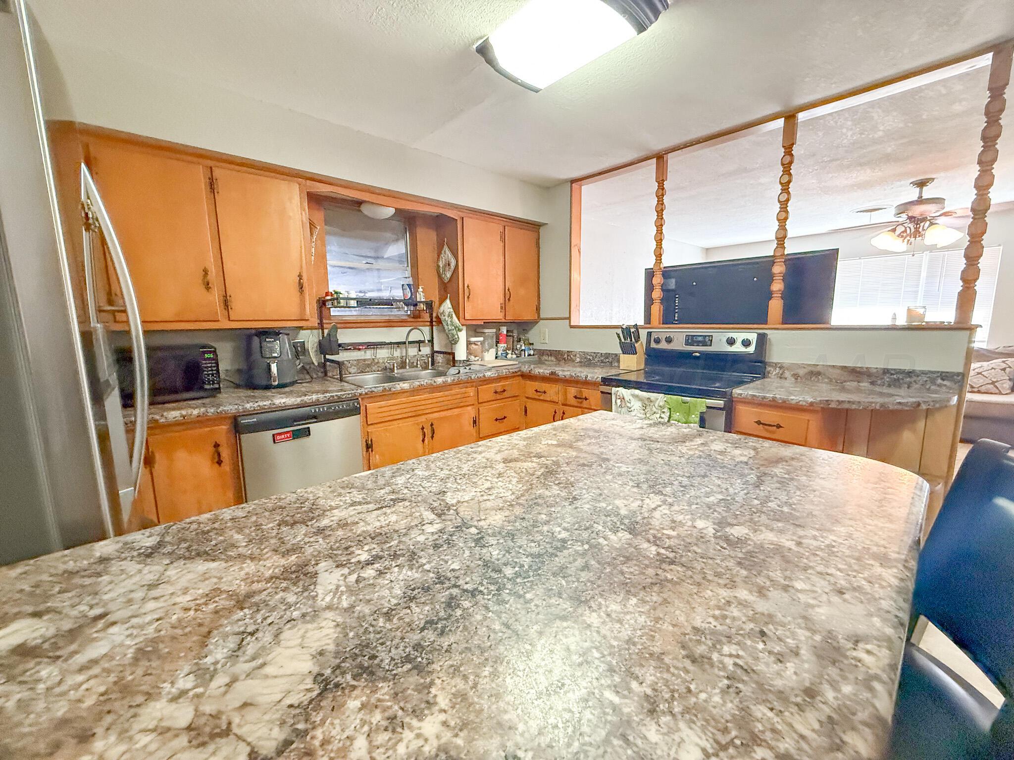 702 South Canadian Street Wheeler, TX 79096 - Photo 17 of 47 a kitchen with kitchen island a sink a counter top space and living room area