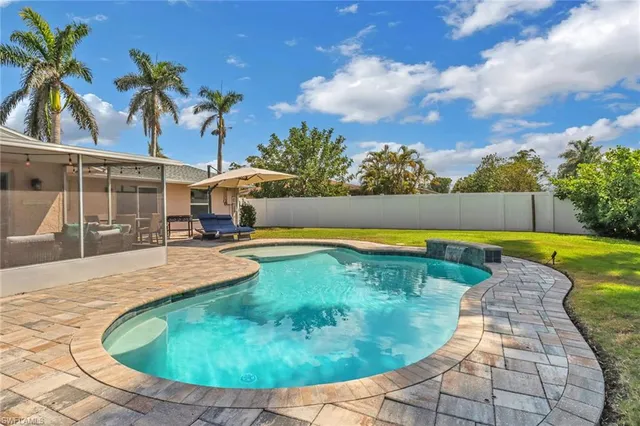 a view of a swimming pool with a lounge chair and palm trees