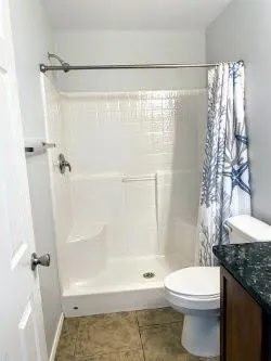 a bathroom with a granite countertop toilet and a shower