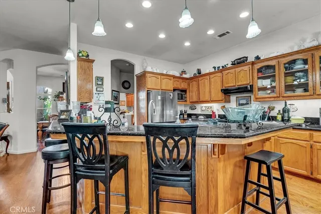 a kitchen with stainless steel appliances granite countertop a sink a stove and a wooden floors