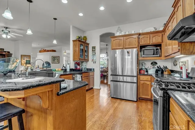 a large kitchen with granite countertop a sink and white cabinets with wooden floor