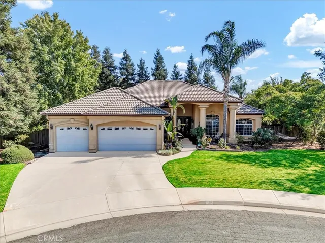 a front view of a house with a garden and a tree