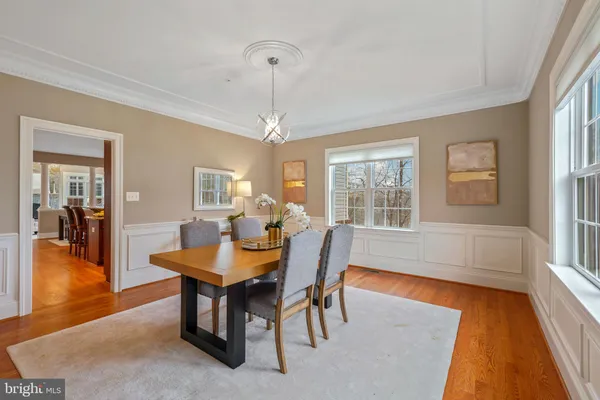 a dining room with wooden floor a chandelier a wooden table and chairs