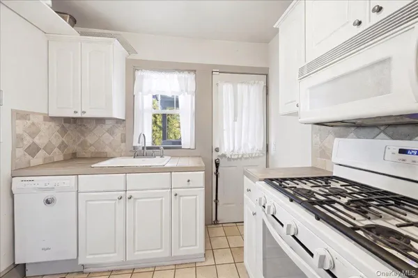 a kitchen with white cabinets and appliances