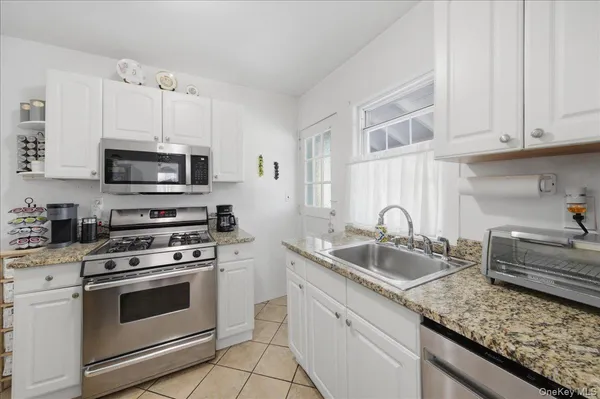 a kitchen with granite countertop a sink stove and microwave