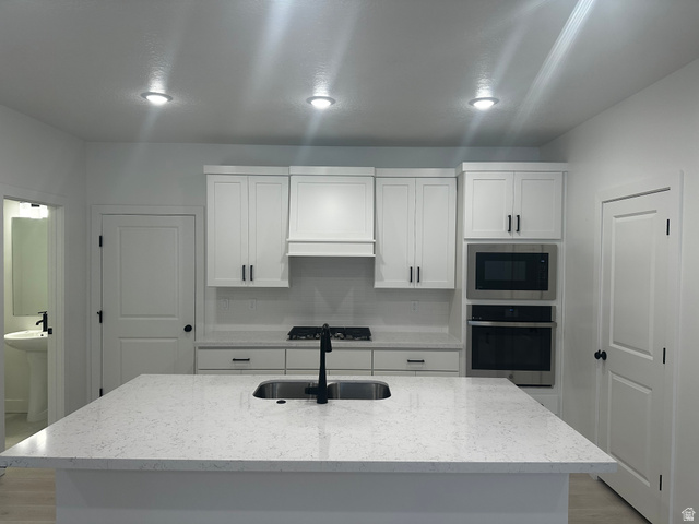 61 South Lunar Way Mapleton, UT 84664 - Photo 4 of 15 Kitchen featuring stainless steel appliances, light stone countertops, white cabinetry, a center island with sink, and tasteful backsplash