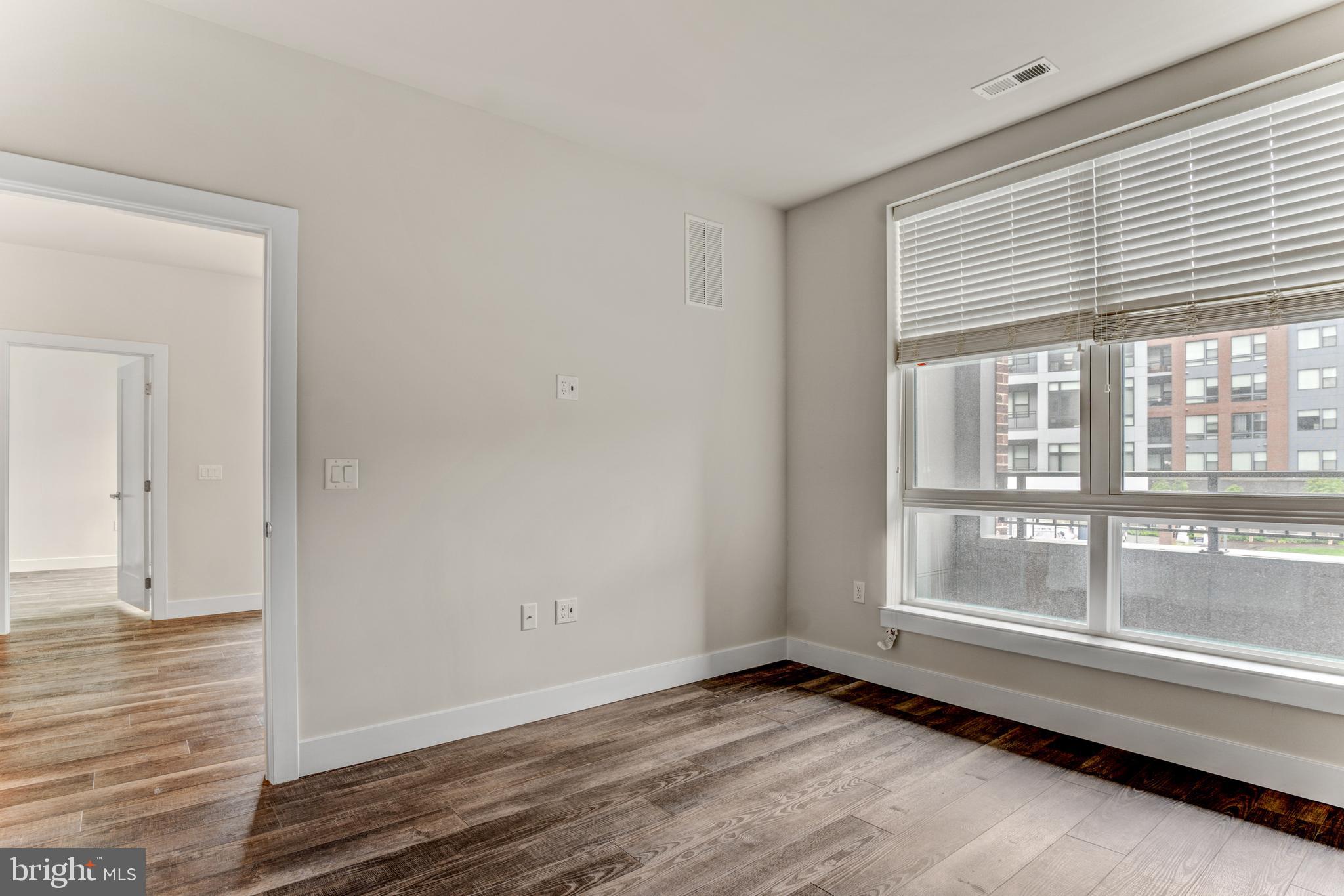 1761 Old Meadow Road, Unit 209 McLean, VA 22102 - Photo 11 of 49 a view of an empty room with wooden floor and a window