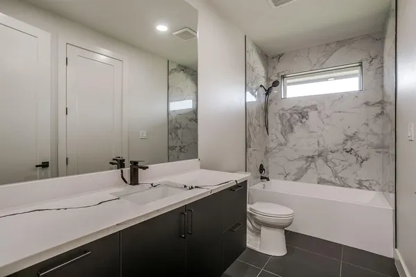 a bathroom with a granite countertop sink toilet mirror and shower