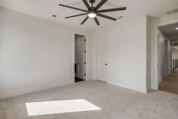 an empty room with windows and chandelier fan