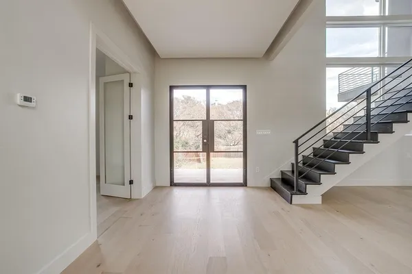 a view of an empty room with wooden floor and windows