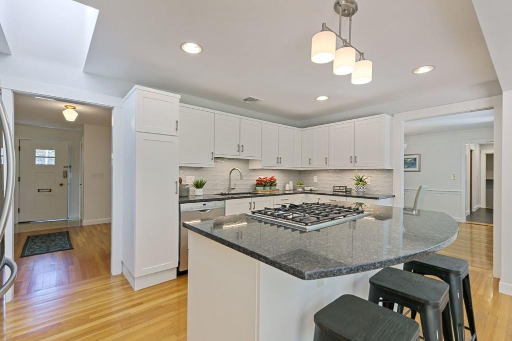9 Baskin Road Lexington, MA 02421 - Photo 14 of 39 a kitchen with stainless steel appliances granite countertop a stove a refrigerator a sink a dining table and chairs with wooden floor