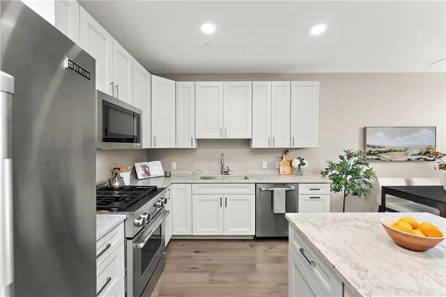 a kitchen with granite countertop a refrigerator a stove a sink and a dining table with wooden floor