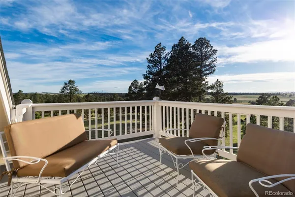 a view of a balcony with wooden chairs and floor to ceiling window