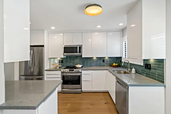 a kitchen with a sink a counter top space stainless steel appliances and cabinets