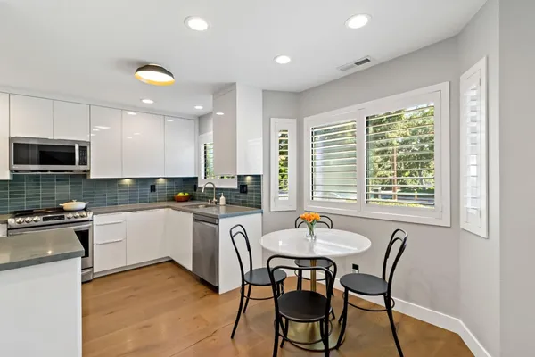 a kitchen with a dining table chairs stainless steel appliances and cabinets