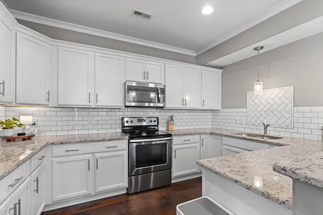a kitchen with granite countertop a sink stainless steel appliances and white cabinets