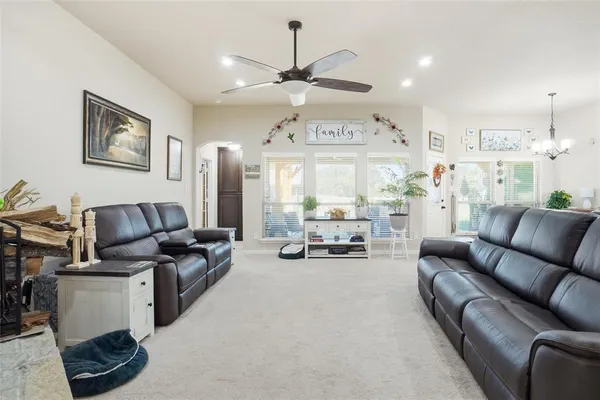 a living room with furniture kitchen view and a chandelier